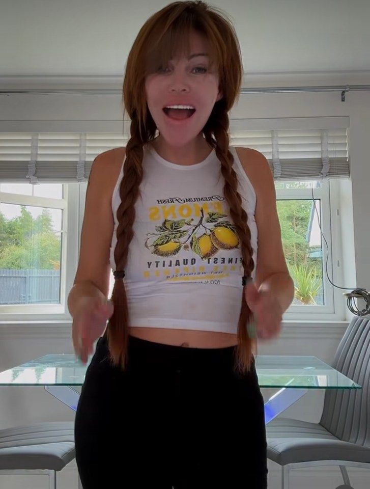 Amanda Love, a woman with long braided hair, wearing a lemon-print tank top and black pants, speaking to the camera.
