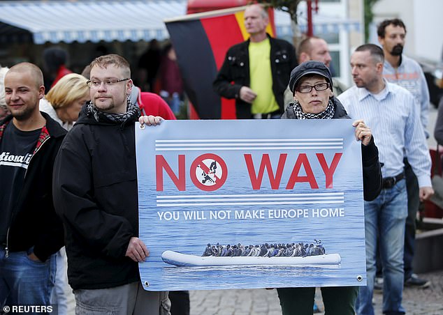 Supporters of the far-right National Democratic Party (NPD) hold a placard and a German flag during a march in Riesa, Germany, September 9, 2015