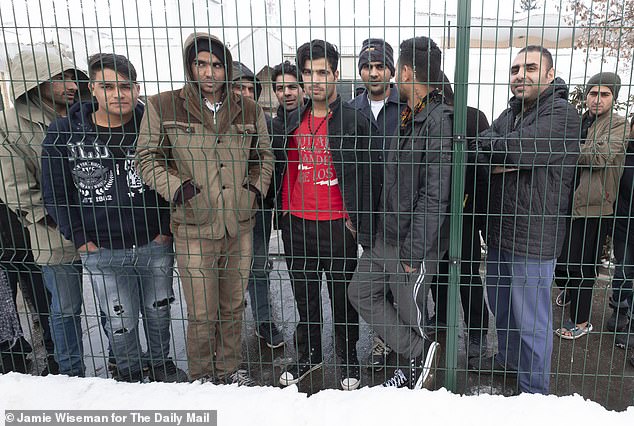Migrants, mainly Iranian, pictured behind the fence of the Adasevci migrant camp in late 2018