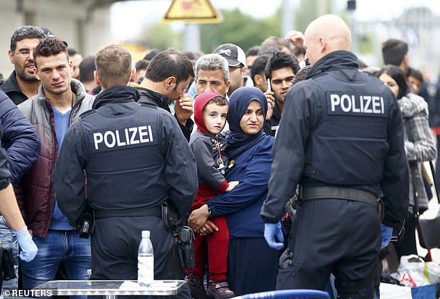 German policemen watch as migrants are taken off a train at a border station in Freilassing, Germany on September 14, 2015