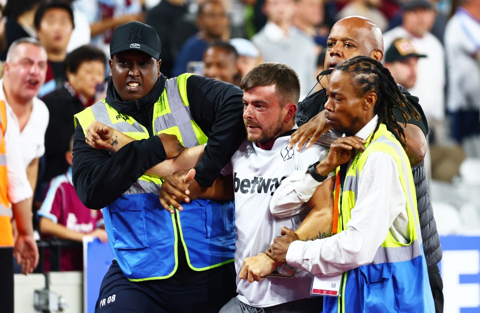 Stewards escorting a West Ham fan from a football match.