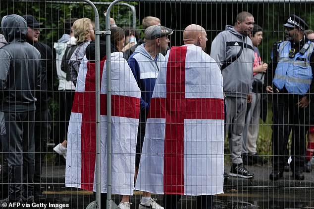 Protesters stand behind fencing during a demonstration calling for the closure of the Bell Hotel in Epping