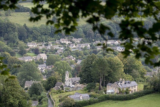 A landscape view of the rolling green fields scattered with limestone houses that the Cotswolds are so well known for