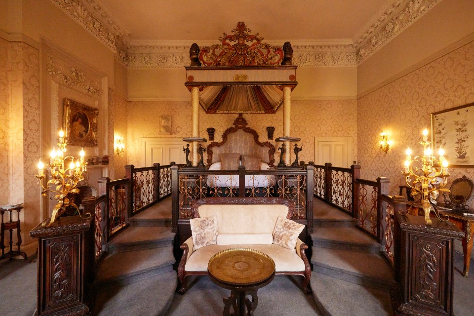 Ornate four-poster bed in a grand bedroom.