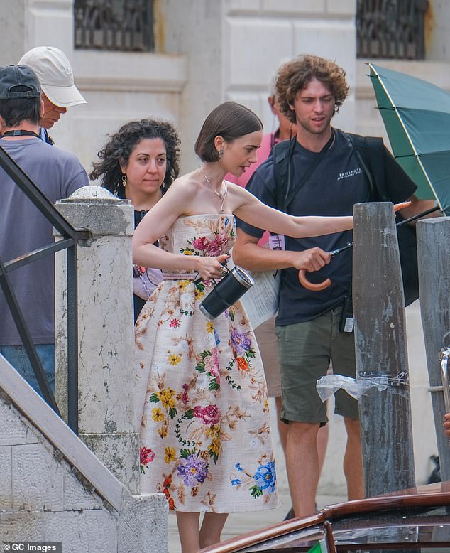 She was helped aboard a boat on Venice's waterways before being passed an umbrella