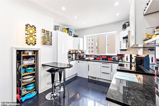 Pictured: The kitchen featuring white cupboards and black surface tops