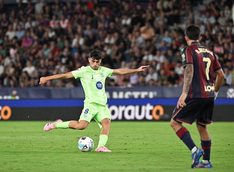 Pedri, #8 for FC Barcelona, kicking a soccer ball.