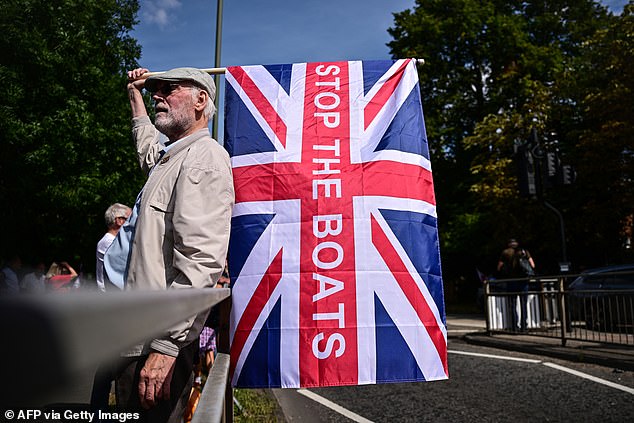 An anti-immigrant protester holds a Union Flag reading 'Stop The Boats' during a protest outside the Sheraton Four Points hotel on Saturday