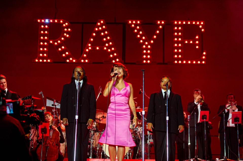 Raye performing onstage with a band.