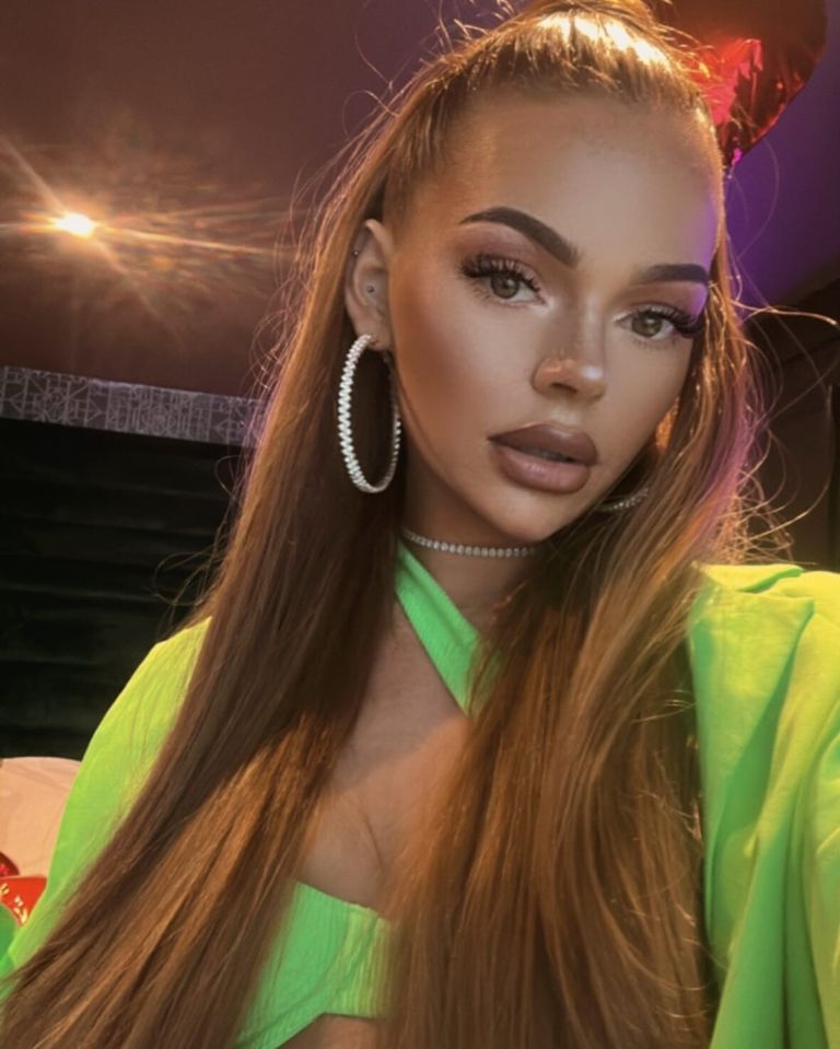 Woman with long brown hair wearing a lime green top and large hoop earrings.