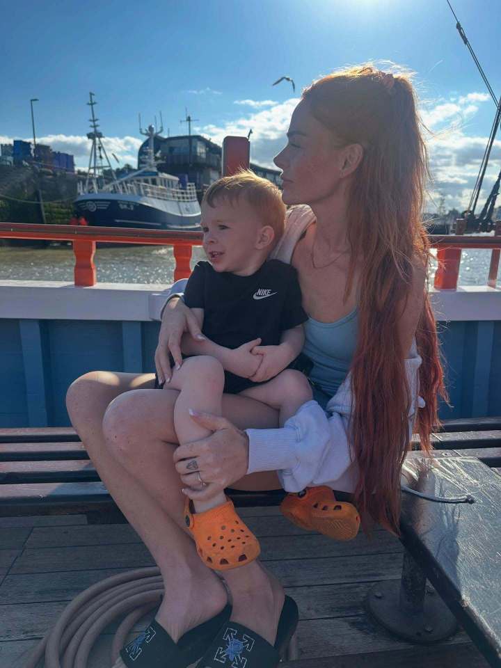 Woman holding her toddler on a boat.