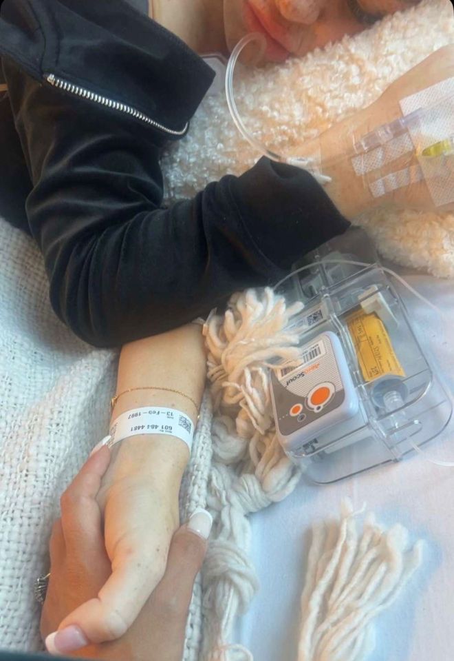 Close-up of a woman's arm with an IV, being held by another person.