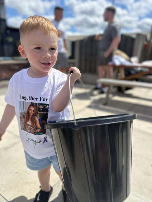 Toddler carrying a bucket, wearing a t-shirt with a photo and the text "Together For Georgia".