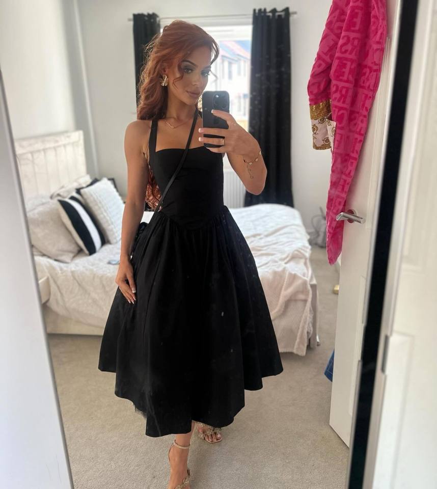 Woman in black dress taking a selfie.