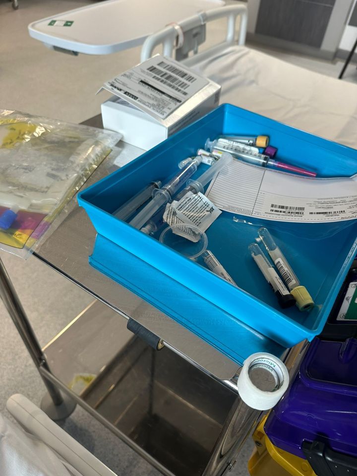 Medical supplies in a blue tray on a hospital cart.