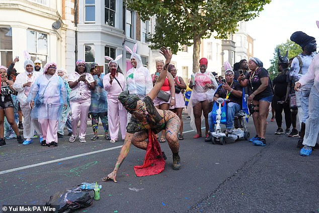 Revellers watch on as a woman dances on the streets of Notting Hill for J'Ouvert