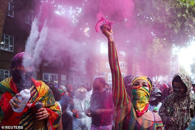 Revellers fire paint and powders into the air during celebrations at sunrise for Notting Hill Carnival