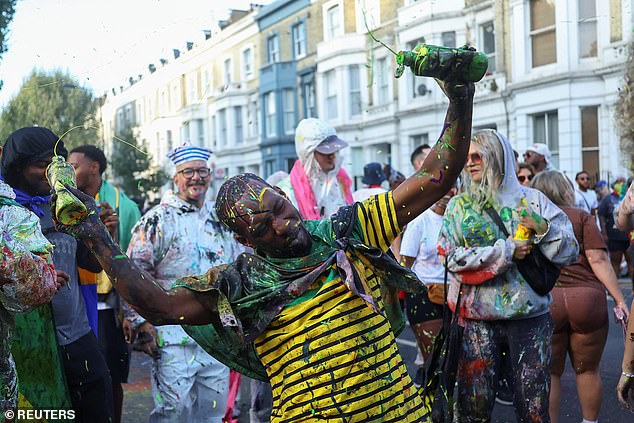 A man dances and sprays paint across the streets during Notting Hill Carnival on Sunday