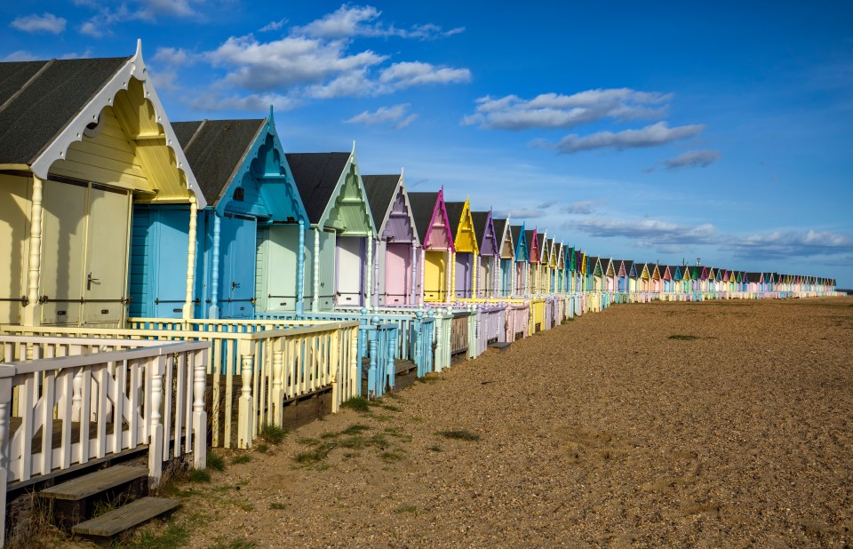 Row of colorful beach huts on a sandy beach.
