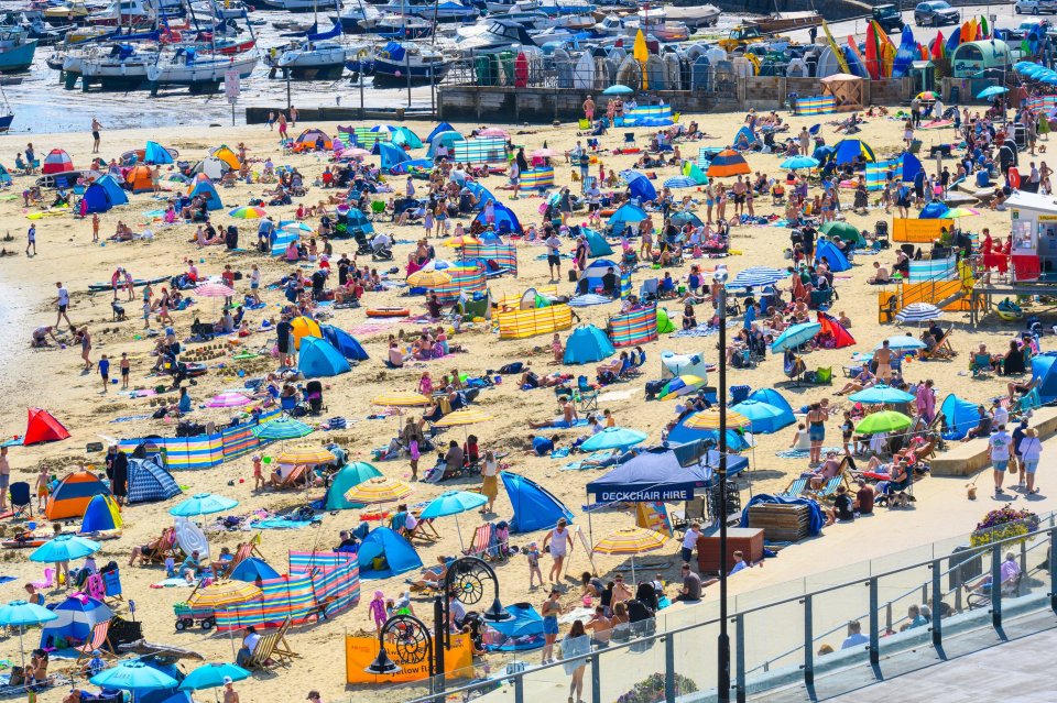 Crowded beach with people enjoying hot weather.