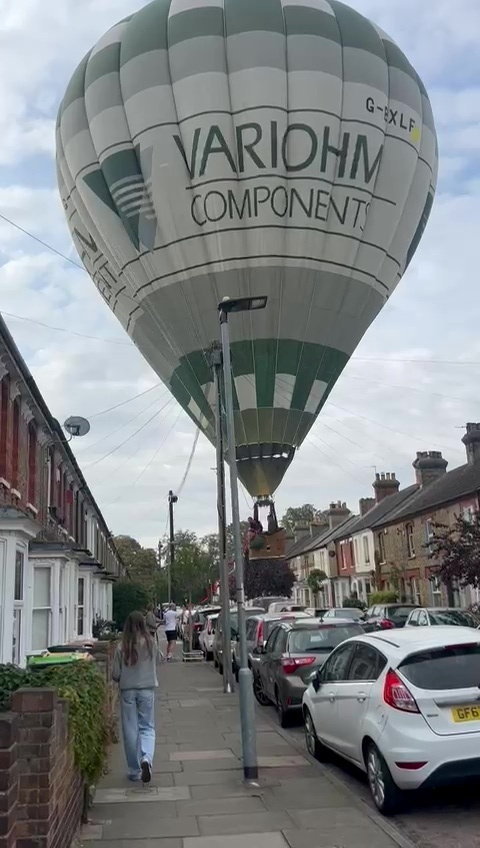 Hot air balloon making an emergency landing in a residential street.
