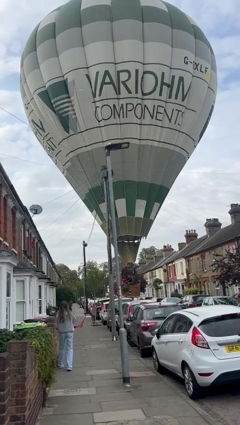 Hot air balloon making an emergency landing in a residential street.