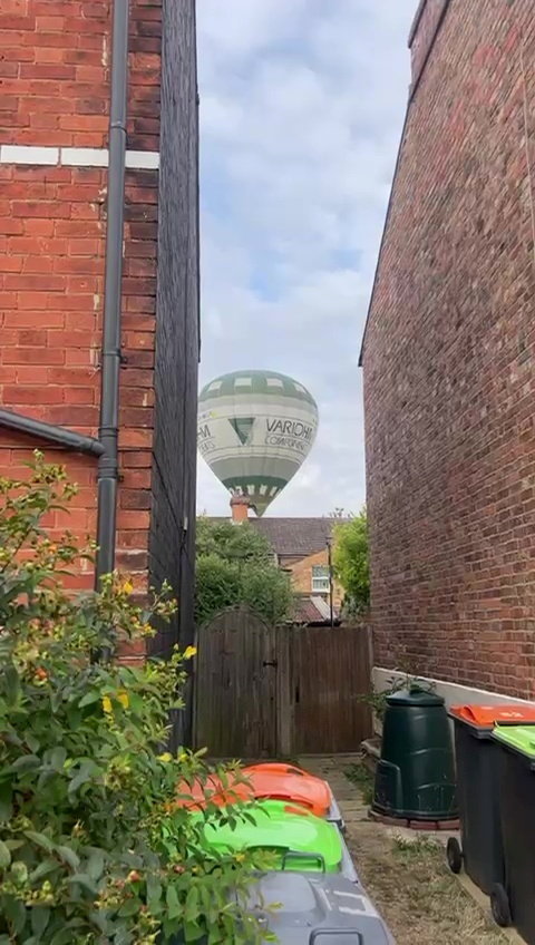 Hot air balloon making an emergency landing between houses.