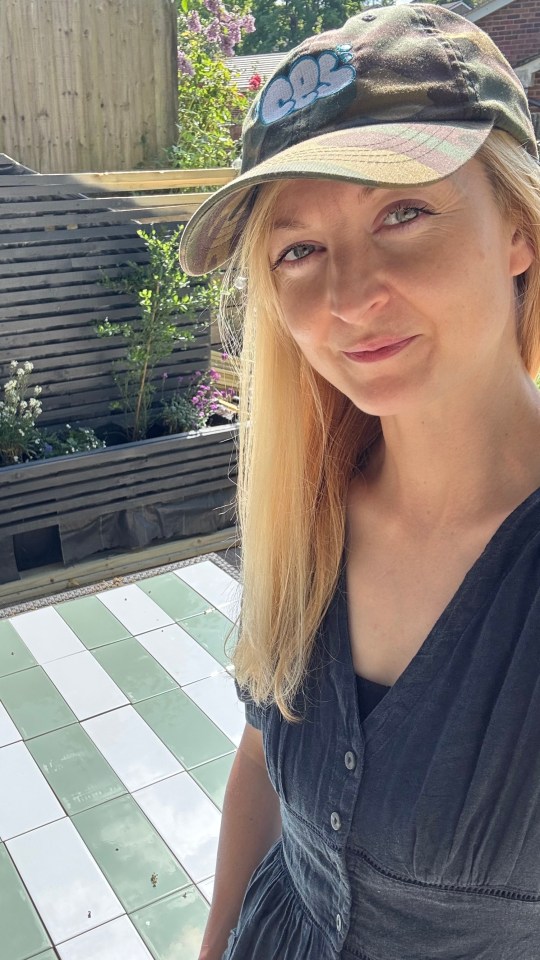 Woman in a camo hat standing in front of a newly tiled patio.