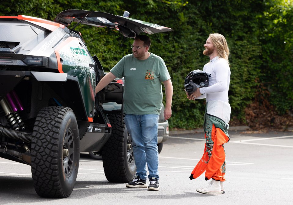 Sam Ryder with a helmet, next to a Dacia Sandrider off-road vehicle.