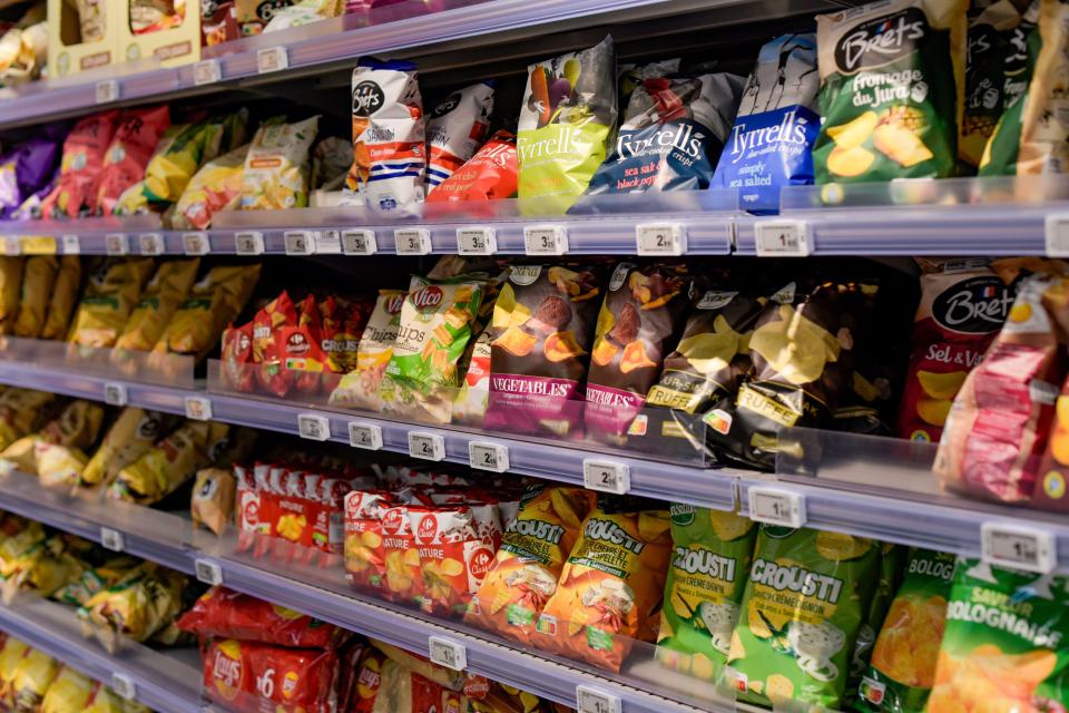 Supermarket shelves stocked with various bags of potato chips.