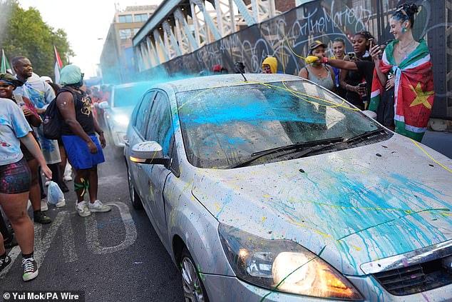 Cars driving through the parade are splattered in paint during J'Ouvert