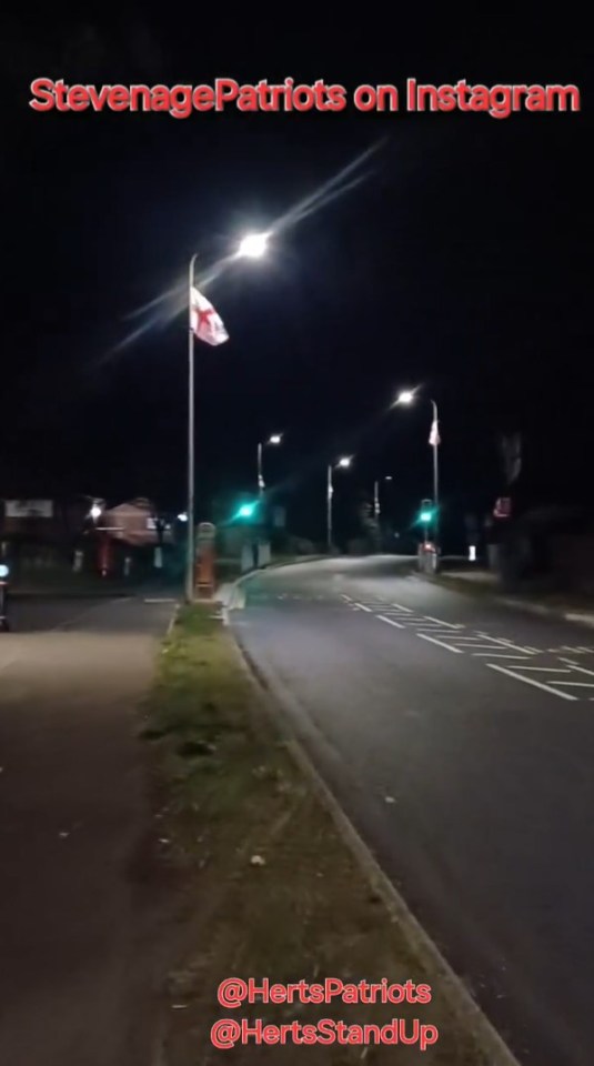 Nighttime photo of a road with a flagpole displaying a flag.