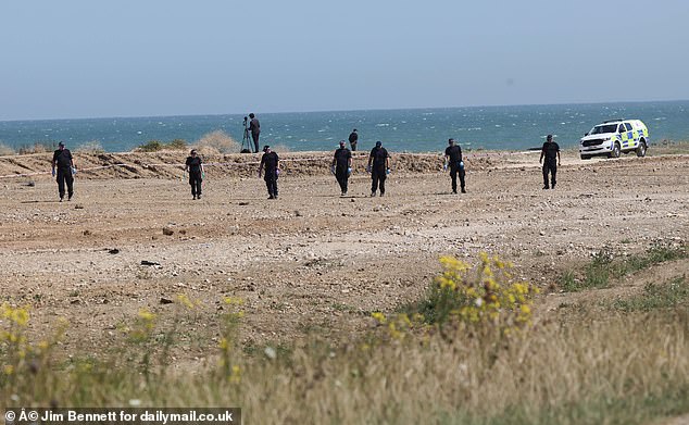 A group of police officers pictured combing an area of the beach in Leysdown-on-Sea