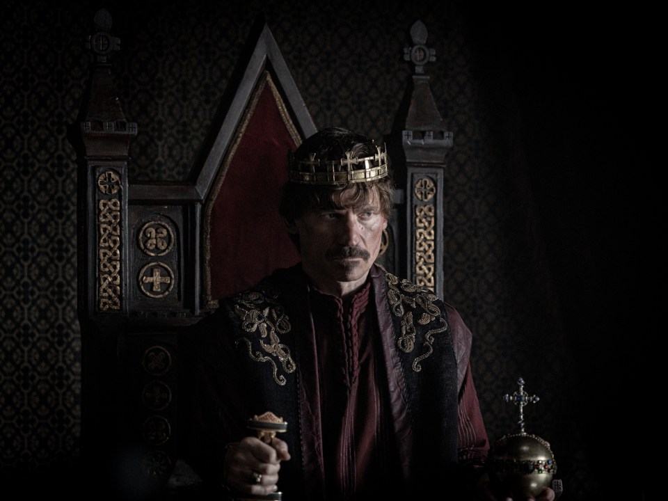 A king sits on his throne holding a scepter and orb.