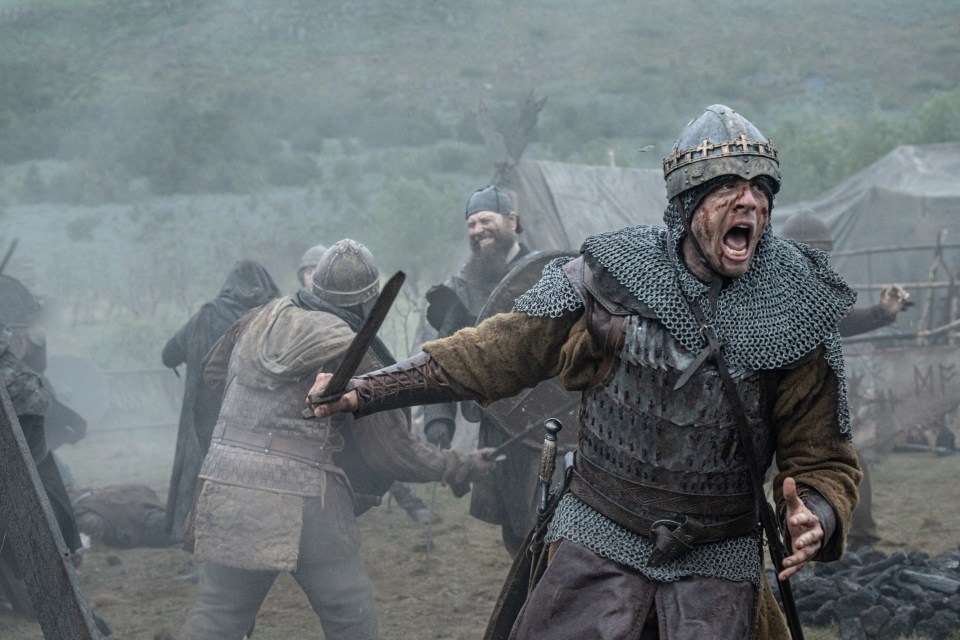 A bloody, screaming warrior in medieval armor during a battle.