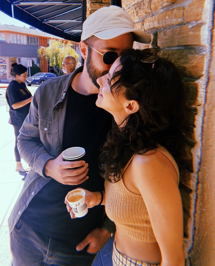 Fernanda and Michael embracing, holding coffee cups.