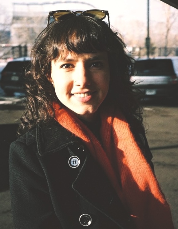Fernanda Fabian, a woman in a black coat and orange scarf.