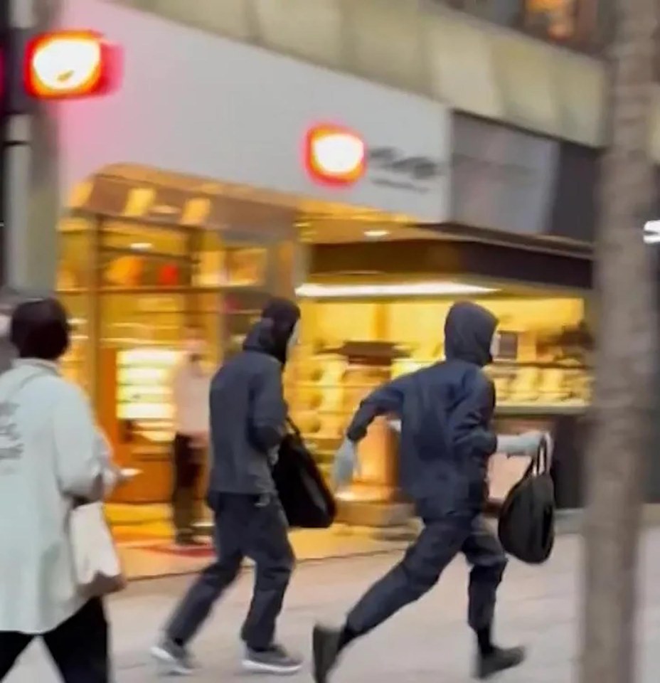 Two people running down a city street carrying bags after a robbery.
