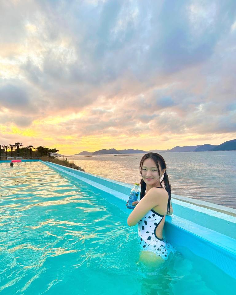 Woman in a swimsuit in a pool at sunset.