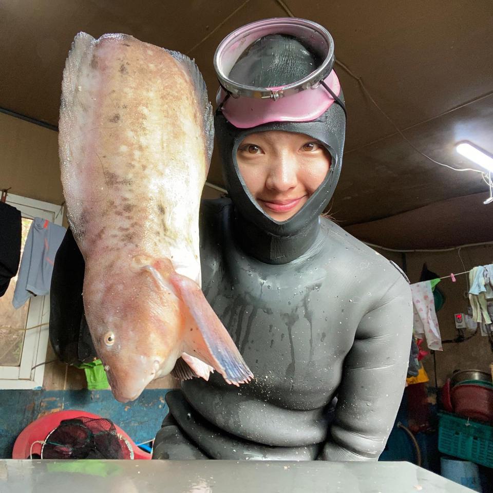 Haenyo woman holding a large fish after freediving.