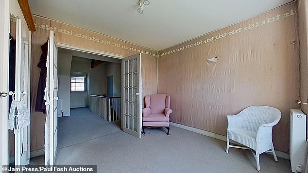 A sitting room in the Devon farmhouse with wide double doors leading to the staircase