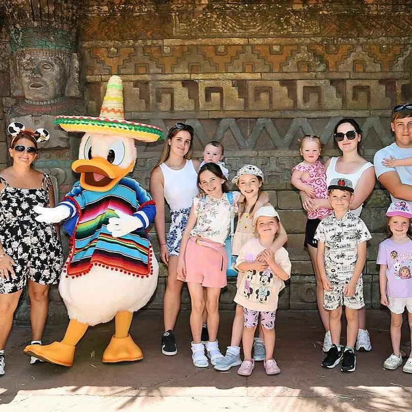 Large family posing with Donald Duck in a Mexican costume at Disney.