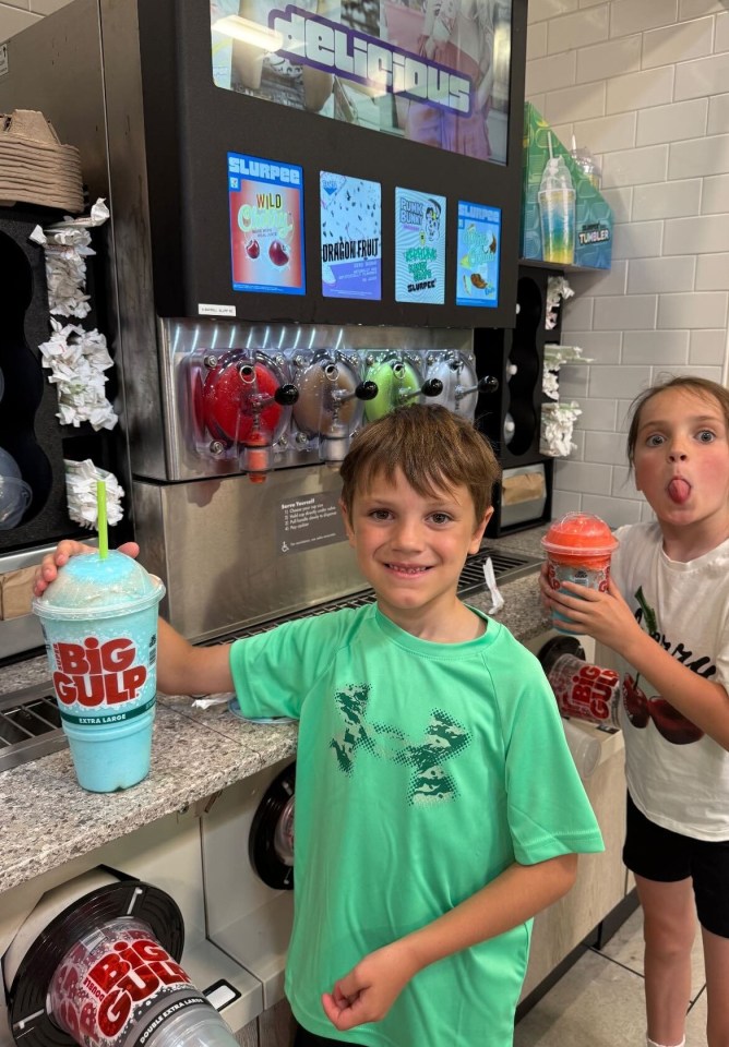 Two children with Slurpees at a convenience store.