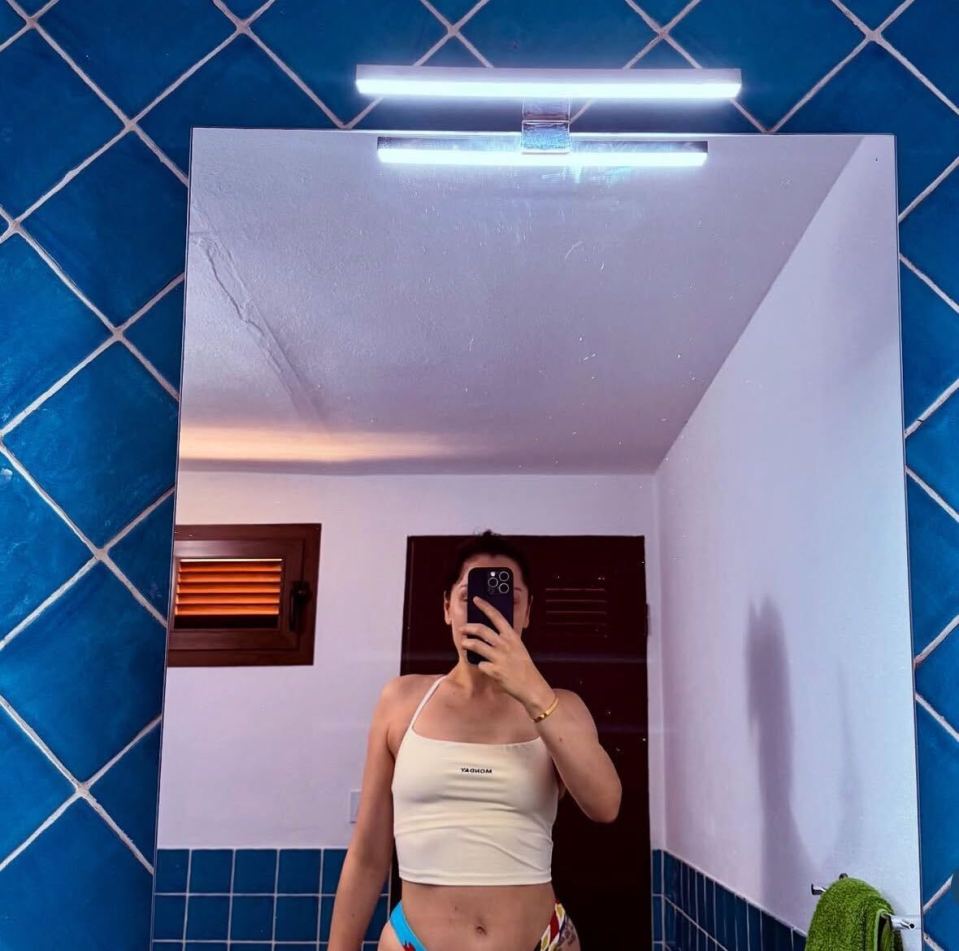 Woman taking a selfie in a bathroom mirror.