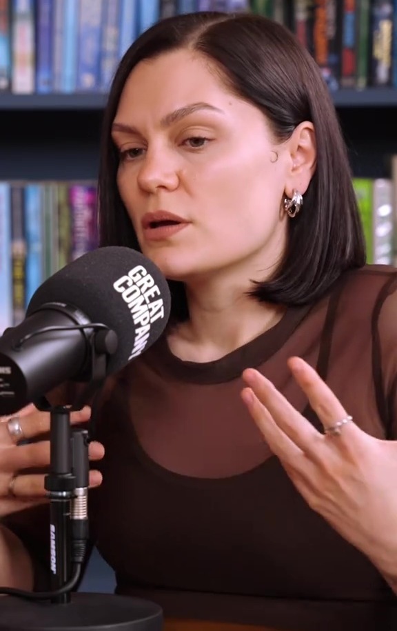 Jessie J speaking into a microphone during a podcast interview.
