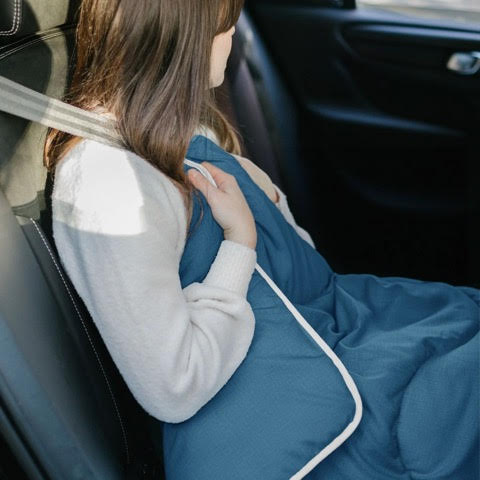 Woman in car using a blue duvet.