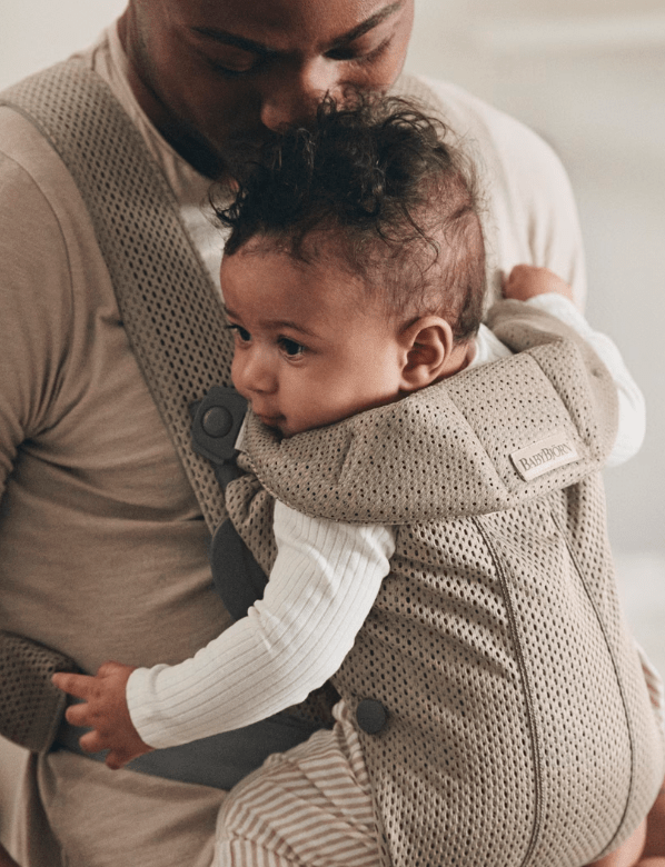 Father holding baby in a BabyBjörn carrier.