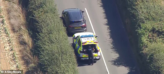 Four individuals, including the pilot, were onboard the small vehicle when it came down near the town of Shanklin on the main road to Newport just before 9.30am (pictured: police attend the scene)
