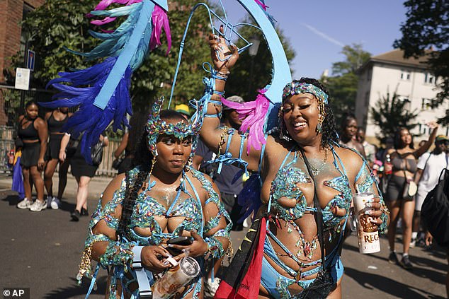 Two carnival attendees are dressed in flamboyant blue outfits as they celebrate in the UK sunshine