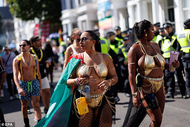 Revellers wearing gold bikinis enjoy the sunshine as they take part in today's festivities